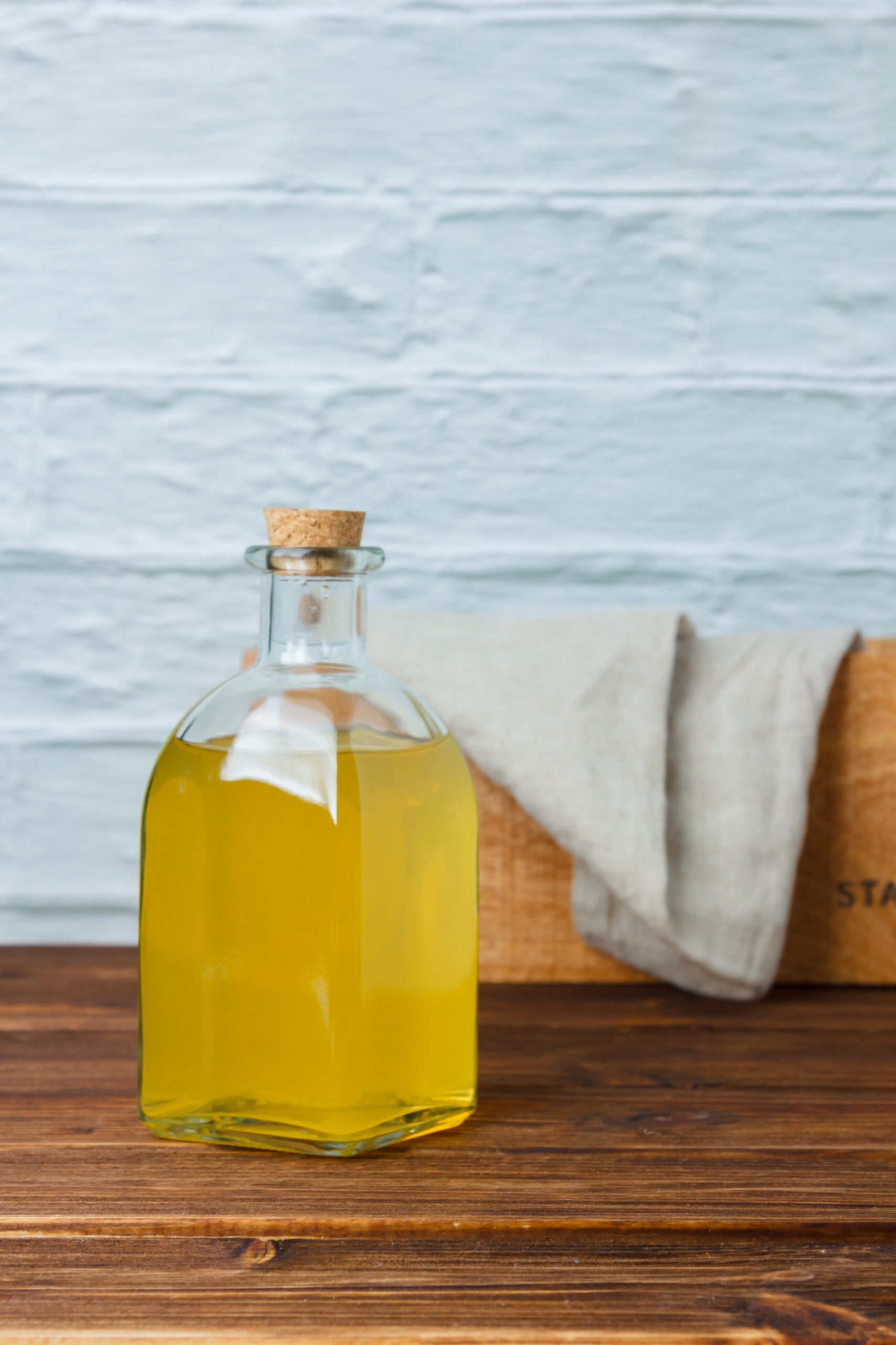 Side view lemon juice jar with wooden crate and white cloth on wooden and white background. vertical space for text